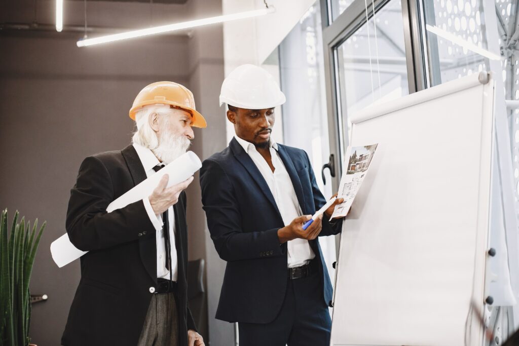 african man black suit old engineer with boss young guy with senior man writing board (1)