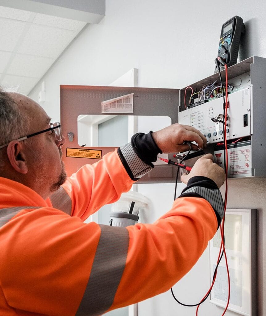 a fire alarm control panel being inspected and tested by a technician