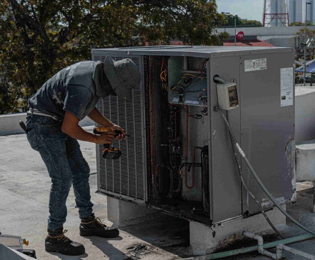 a technician servicing a rooftop chiller unit under a bright sky