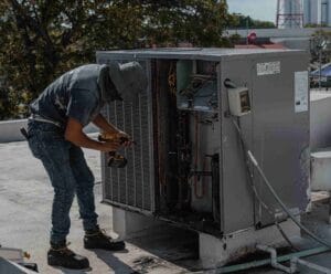 a technician servicing a rooftop chiller unit under a bright sky