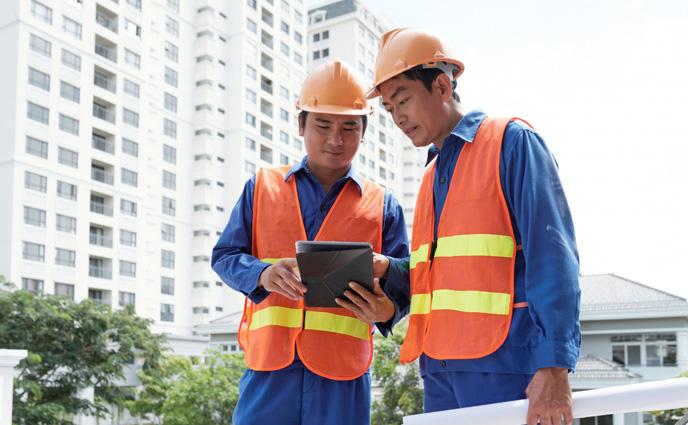 facility manager reviewing a maintenance schedule on a tablet, building plant room in background